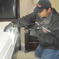Bed bug inspection technician checking a mattress and bed frame for signs of infestation in Milwaukee, WI