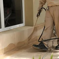 General pest control technician spraying exterior perimeter around a home in Milwaukee, WI