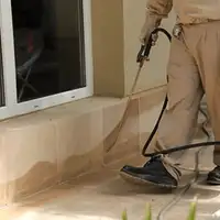 General pest control technician spraying exterior perimeter around a home in Milwaukee, WI