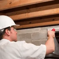 Termite inspection technician checking a basement wall and framing for termite activity in Milwaukee, WI