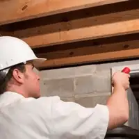 Termite inspection technician checking a basement wall and framing for termite activity in Milwaukee, WI